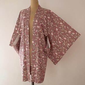 May include: A mauve-coloured kimono with a floral pattern of pink flowers and green leaves.