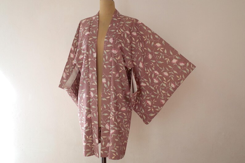May include: A mauve-coloured kimono with a floral pattern of pink flowers and green leaves.