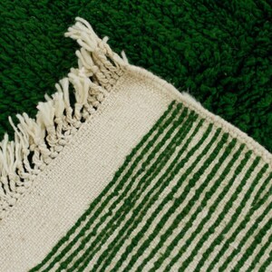 K&ouml;nnte beinhalten: Ein wei&szlig;er und gr&uuml;ner gestreifter Teppich mit Fransenrand. Der Teppich ist aus einem weichen, strukturierten Material.