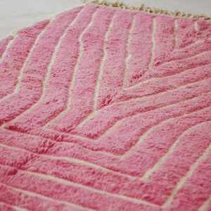 May include: A pink and white rug with a chevron pattern. The rug is made of a soft, fluffy material.