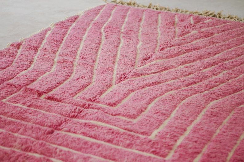 May include: A pink and white rug with a chevron pattern. The rug is made of a soft, fluffy material.