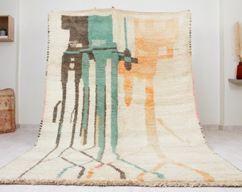 May include: A hand-woven rug with a cream background and abstract designs in shades of brown, teal, and orange.