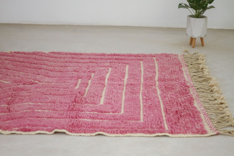 May include: A pink and cream woven rug with a geometric pattern and fringe.