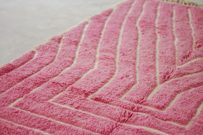 May include: Pink and white chevron patterned rug with a fluffy texture.