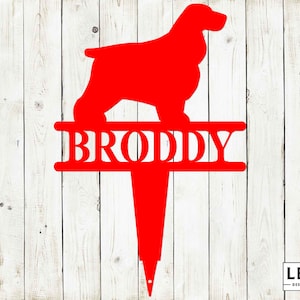May include: Red metal silhouette of a Cocker Spaniel dog with the name "Broddy" on a metal bar above the dog. The silhouette is mounted on a red metal stake.