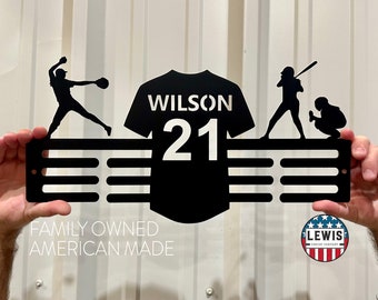 May include: Black metal baseball-themed wall art featuring a jersey with "WILSON 21" and silhouettes of a pitcher, batter, and catcher. The art includes horizontal slots for hanging and the text "FAMILY OWNED AMERICAN MADE".
