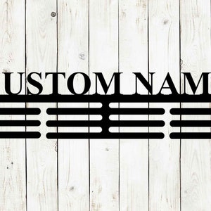 May include: Black metal sign with the words "CUSTOM NAME" at the top. Below the text are three horizontal rows of evenly spaced slots. The sign is mounted on a white wooden plank background.