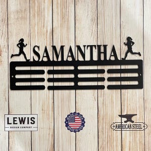 May include: Black metal medal display rack with the name "SAMANTHA" and two running figures. The rack has five slots for medals. The rack is made in the USA.