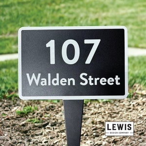 May include: Black metal yard sign with white text that reads "107 Walden Street".