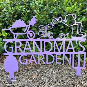 Puede incluir: Se&ntilde;al de jard&iacute;n de metal morado con el texto "Grandma's Garden" y una carretilla, una mariposa, una planta, un caracol y una persona regando una planta.