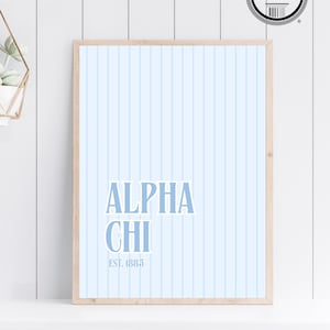 Può includere: Una stampa incorniciata con uno sfondo blu chiaro e strisce verticali bianche. La stampa presenta il testo "ALPHA CHI" in blu con il testo "EST. 1885" sotto.