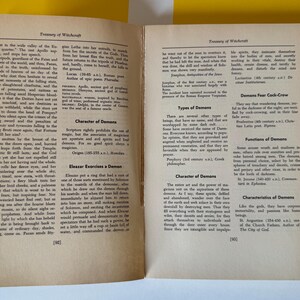 May include: Open book with text on aged paper. The pages are from a book titled "Treasury of Witchcraft". The text includes sections on demons, their characteristics, and functions. The book is open on a yellow surface.