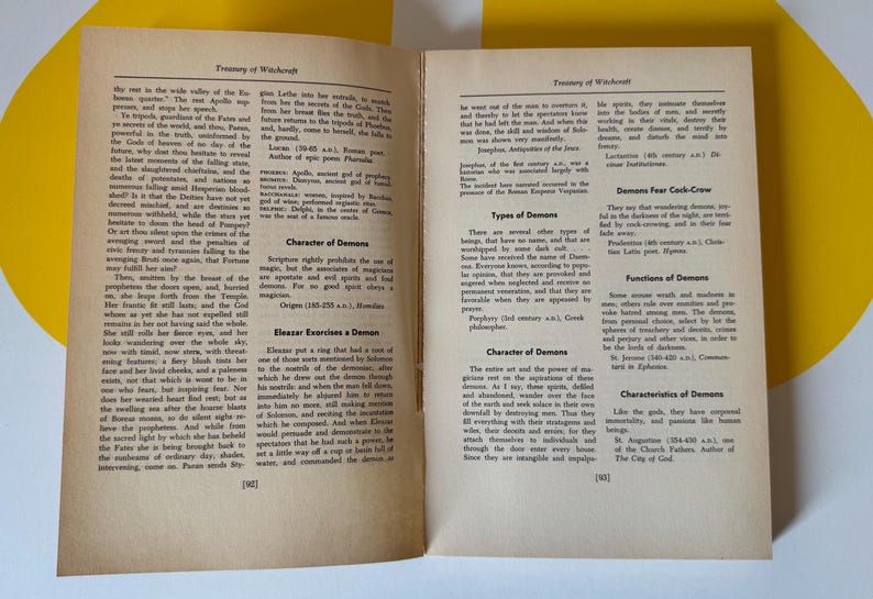 May include: Open book with text on aged paper. The pages are from a book titled "Treasury of Witchcraft". The text includes sections on demons, their characteristics, and functions. The book is open on a yellow surface.