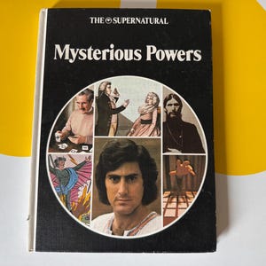 May include: A vintage book titled "Mysterious Powers" with a black cover and white text. The cover features a circular collage of images, including portraits and illustrations. The book's title is in large, bold letters.