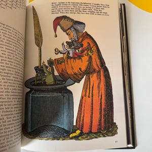May include: An illustration from a vintage book depicts a robed figure with a tall hat, holding small figures. The figure is leaning over a large inkwell. The image is in shades of orange, black, and white, with text in the background.