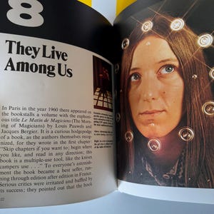 May include: Open book page with the title "They Live Among Us" and a photo of a woman with lights around her head. The number "8" is at the top left. Text describes a book about the morning of magicians.
