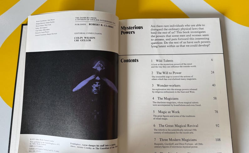 May include: Open book with the title "Mysterious Powers" and a table of contents. The left page features a black and white image of a person with their hands over their eyes. The book explores the potential of latent human abilities.