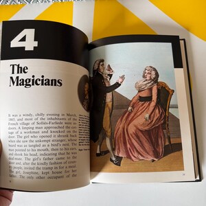 May include: Open book with the title "The Magicians" and a vintage illustration of two people in period clothing. The illustration depicts a man gesturing and a woman seated in a chair. The page numbers are visible.