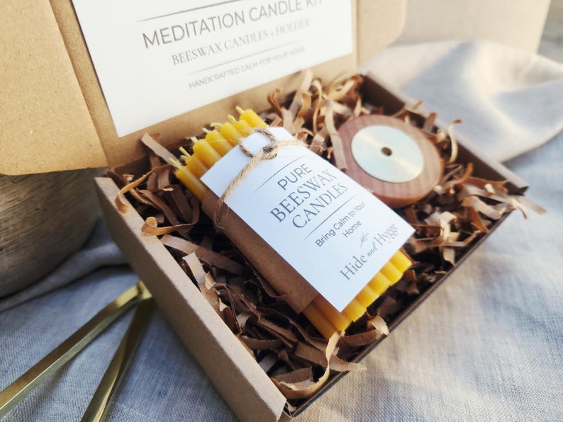 May include: A meditation candle kit in a cardboard box. The kit includes a bundle of yellow beeswax candles, a wooden candle holder, and decorative paper. The label reads "Pure Beeswax Candles" and "Bring Calm to Your Home."