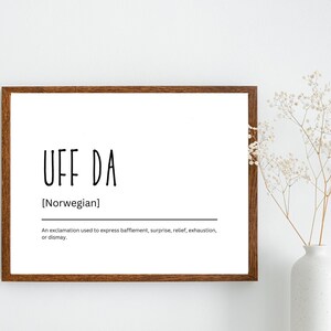 Könnte beinhalten: Ein gerahmter Druck mit dem Text "UFF DA" in schwarzen Buchstaben, mit der Definition "[Norwegisch] Ein Ausruf, der verwendet wird, um Verwirrung, Überraschung, Erleichterung, Erschöpfung oder Verzweiflung auszudrücken."