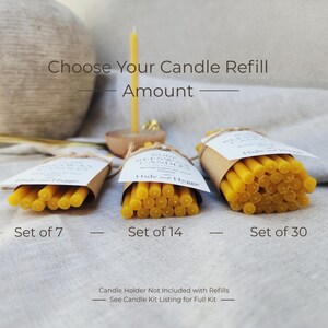 K&ouml;nnte beinhalten: Drei B&uuml;ndel gelber Kerzennachf&uuml;llungen, gekennzeichnet als Sets mit 7, 14 und 30. Der Text "Choose Your Candle Refill Amount" steht &uuml;ber den B&uuml;ndeln. Die Kerzen sind in braunes Papier mit wei&szlig;en Etiketten gewickelt.