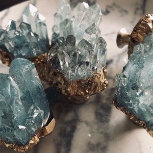 May include: Four crystal drawer pulls with gold accents. Each pull features a cluster of clear blue crystals with a gold base.