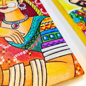 May include: A colorful painting of a woman wearing a red and yellow sari with intricate patterns. The woman has dark hair and is wearing a large, ornate necklace. The painting is done in a vibrant style with bold colors and lines.