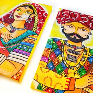 May include: Two colorful paintings on canvas featuring a woman and a man in traditional Indian clothing. The woman is wearing a red and yellow sari with intricate patterns and jewelry. The man is wearing a red turban and a colorful patterned shirt with a silver necklace. Both paintings have a yellow background.