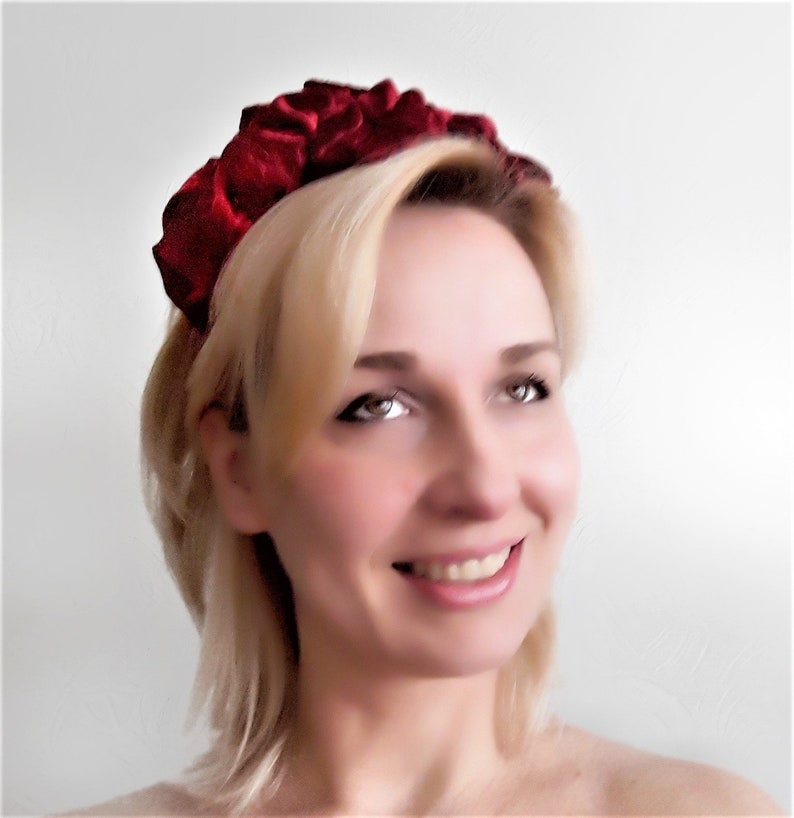 Puede incluir: Una diadema de terciopelo rojo con un dise&ntilde;o fruncido y plisado. La diadema la lleva una persona con el pelo rubio.