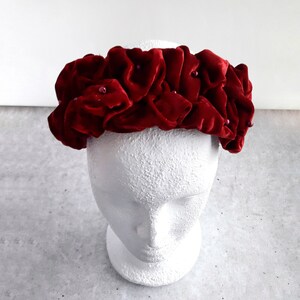 Puede incluir: Una diadema de terciopelo burdeos con un dise&ntilde;o fruncido y peque&ntilde;as cuentas rojas.