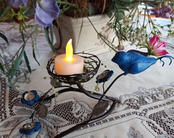 Portavelas de metal con forma de pájaro azul y nido floral