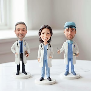 Op de afbeelding: Drie op maat gemaakte bobblehead-figuurtjes die medische professionals voorstellen. Het linkerfiguur draagt een witte jas, blauwe das en donkere broek. Het middelste figuur draagt een witte jas en blauwe scrubs met stethoscoop. Het rechterfiguur draagt scrubs, een operatiemuts en een witte jas.