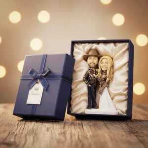 personalized bobblehead gift set displayed in an open navy blue gift box with satin lining, placed next to a matching gift box with a bow, highlighting its value as a unique and thoughtful gift for a hunting couple.