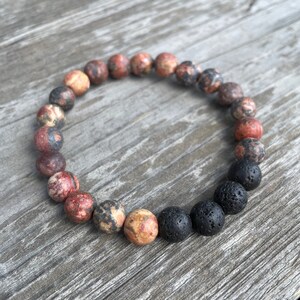 May include: A beaded bracelet with red, brown and white speckled beads and black lava rock beads.