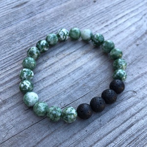 May include: A green and white agate stone bracelet with black lava beads. The bracelet is made of round beads and is approximately 18 cm in length.