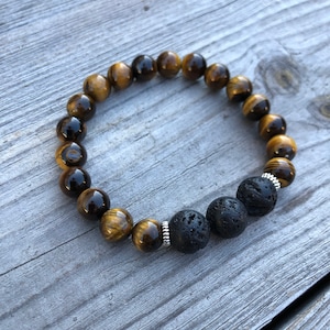May include: A brown and gold tiger's eye beaded bracelet with three black lava rock beads and silver spacers.
