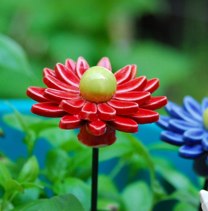 K&ouml;nnte beinhalten: Eine rote Keramikblume mit gr&uuml;nem Zentrum, auf einem gr&uuml;nen Stiel, vor gr&uuml;nem Hintergrund.