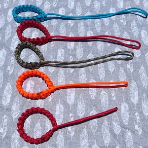 May include: Five colorful paracord bracelets with loops for attaching to keys or a bag. The bracelets are made of different colors of paracord, including blue, red, green, orange, and red.