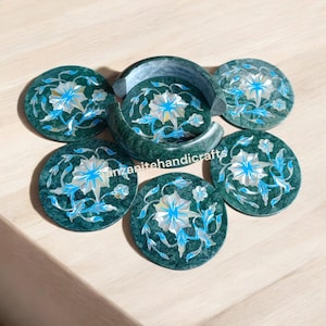 Könnte beinhalten: Satz von sechs Untersetzern aus grünem Marmor mit aufwendigen floralen Designs in Blau und Weiß. Die Untersetzer sind kreisförmig angeordnet, mit einem passenden Untersetzer in der Mitte.