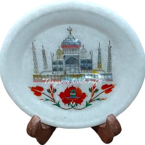 Könnte beinhalten: Weiße Marmorplatte mit einem bunten Intarsienmuster des Taj Mahal und einer roten Blume. Die Platte steht auf einem Holzständer.
