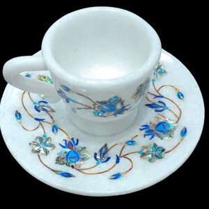 Könnte beinhalten: Weißes Marmor-Teetassen- und Untertassen-Set mit aufwendigen floralen Designs, die mit blauem und irisierendem Perlmutt eingelegt sind.
