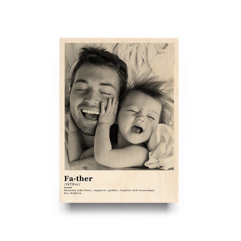May include: Black and white photo of a father and daughter laughing together. The photo is printed on a wooden background with the word "Father" defined below the photo.