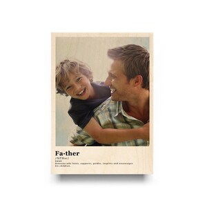 May include: A father and son are smiling at each other. The image is a wood print with the word "Father" and a definition of the word.