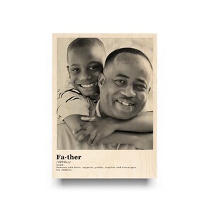 May include: A black and white photo of a father and son hugging. The photo is printed on a wood background with the definition of the word "father" printed below the photo.