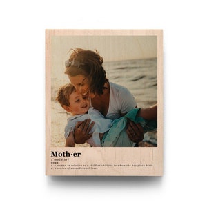 May include: A wood print with a photo of a mother and child hugging on a beach. The print has the word "Mother" with a definition below it.