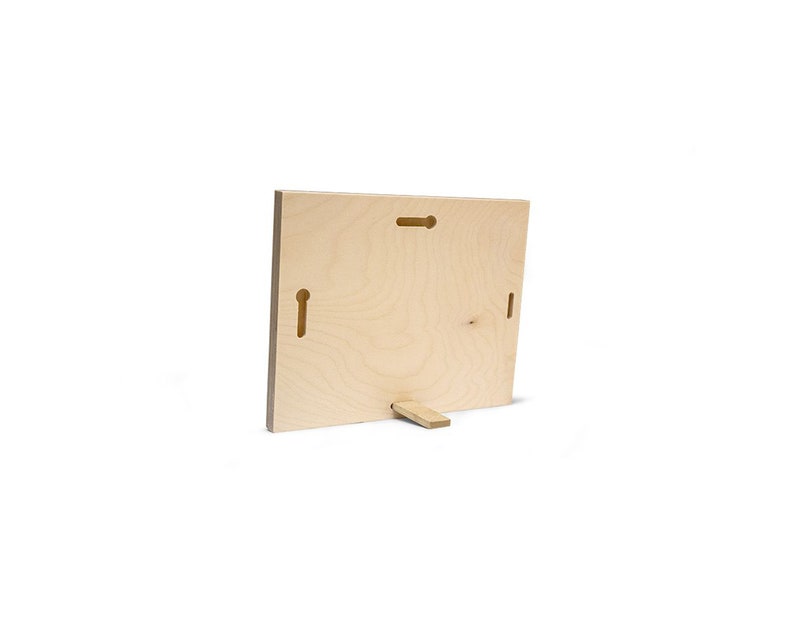 May include: A light wood photo frame with a stand on the back. The frame has two holes on the back for hanging.