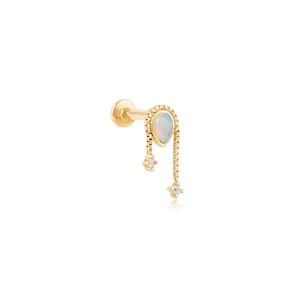 May include: A gold-colored earring with a pear-shaped opal stone and two dangling clear gemstones. The earring has a post for piercing and a decorative chain design.