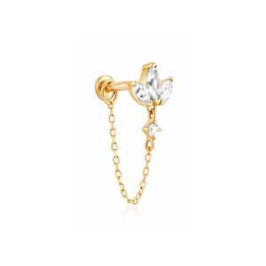 May include: A gold-toned flat back stud earring featuring a lotus-shaped top set with three marquise-cut clear stones. A delicate gold chain connects the stud to a small dangling charm featuring a single round clear stone set in a gold frame.