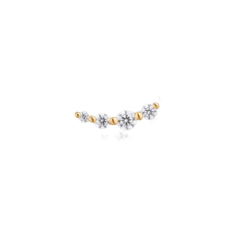 May include: A curved gold earring featuring four round brilliant-cut clear stones of varying sizes arranged in a row, separated by small polished gold beads. The design follows a gentle arc, showcasing a bright metallic finish and clear stones.