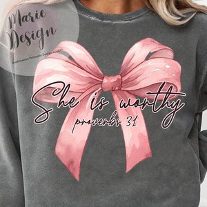 May include: A gray sweatshirt with a pink watercolor bow and the text "She is worthy Proverbs 31" printed on the front.
